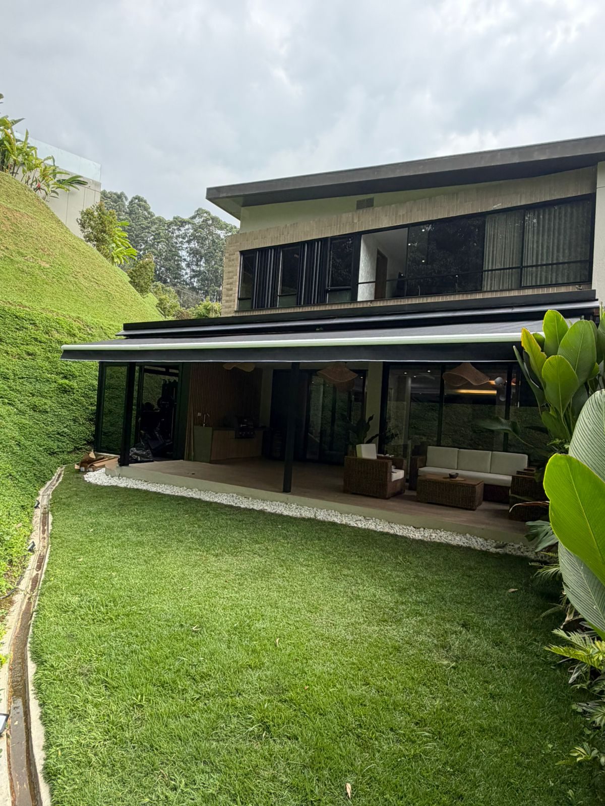 Banneta retráctil instalada sobre terraza de casa moderna con jardín