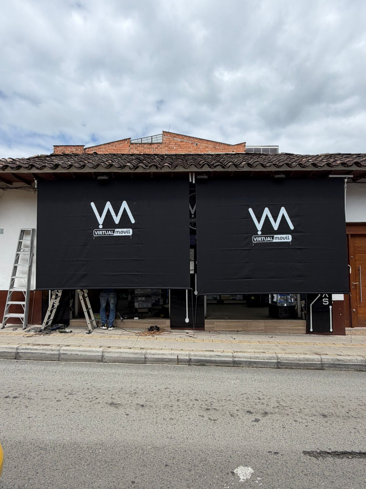 Guillotina enrollable vertical negra con logo en fachada colonial